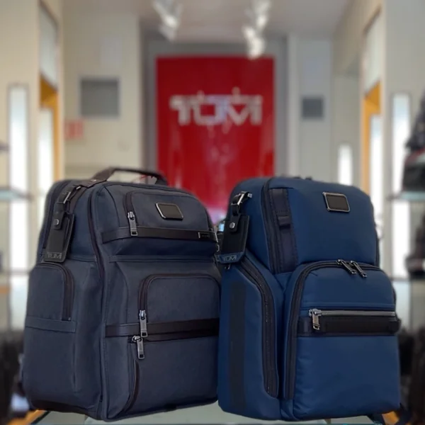 Two navy TUMI Alpha Bravo backpacks in front of the TUMI sign at TUMI Wellesley